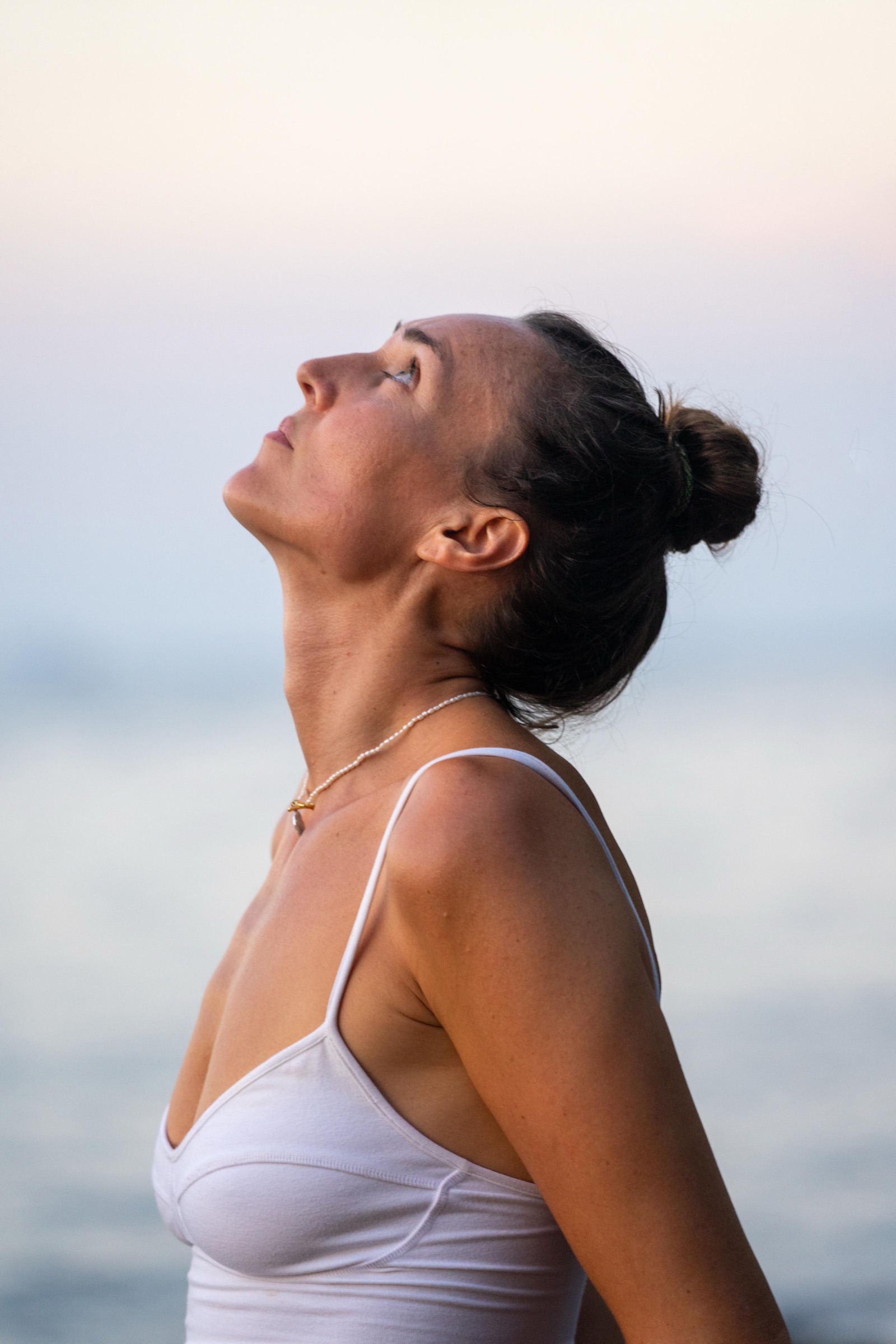Christa breathing deeply with her face lifted toward the sky at sunset